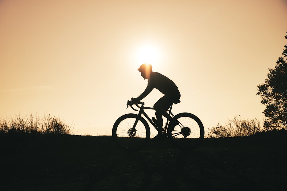 a man riding a bike down a hill at sunset