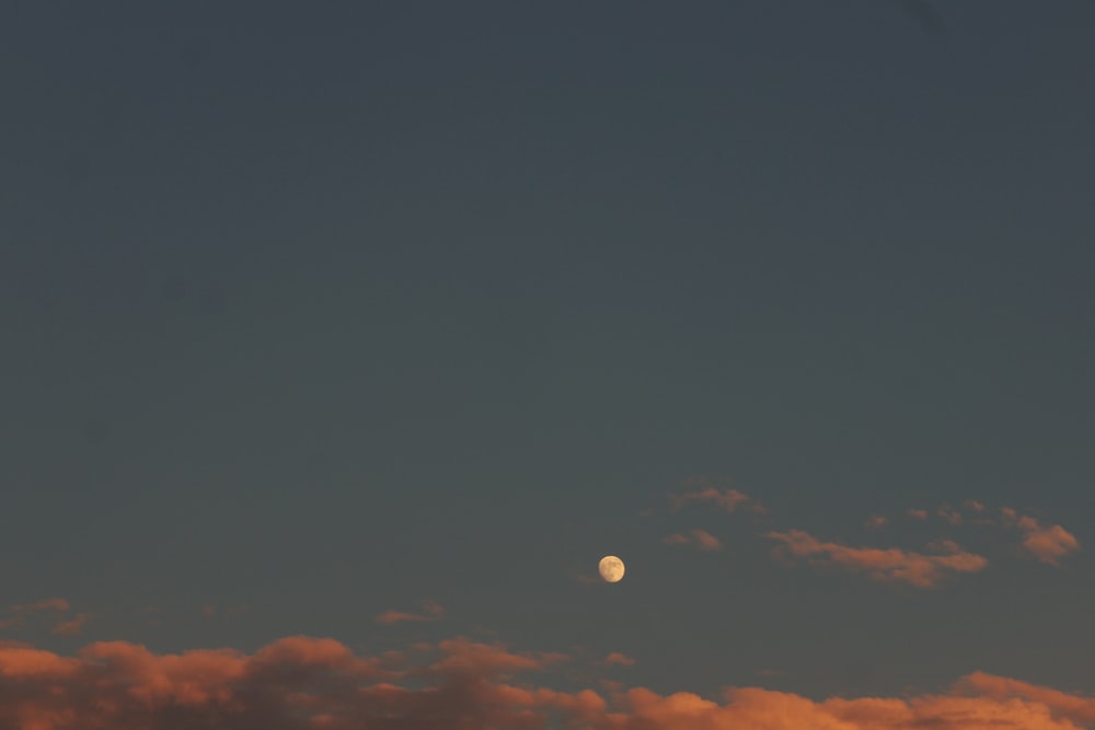 a plane flying in the sky with the moon in the distance