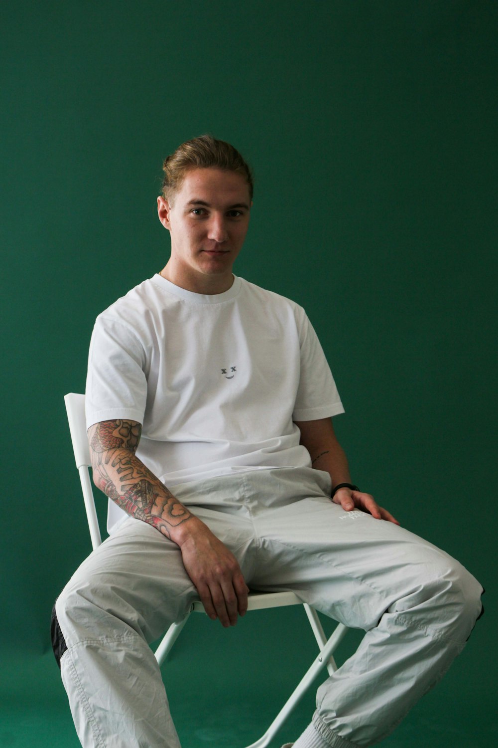 a man with tattoos sitting in a white chair