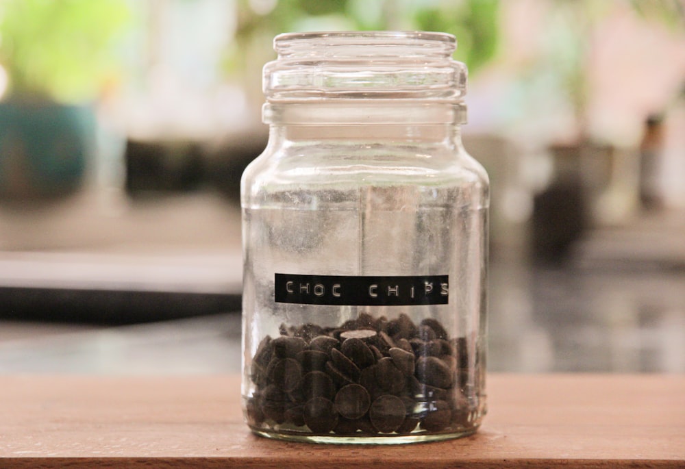 a glass jar filled with coffee beans on top of a wooden table