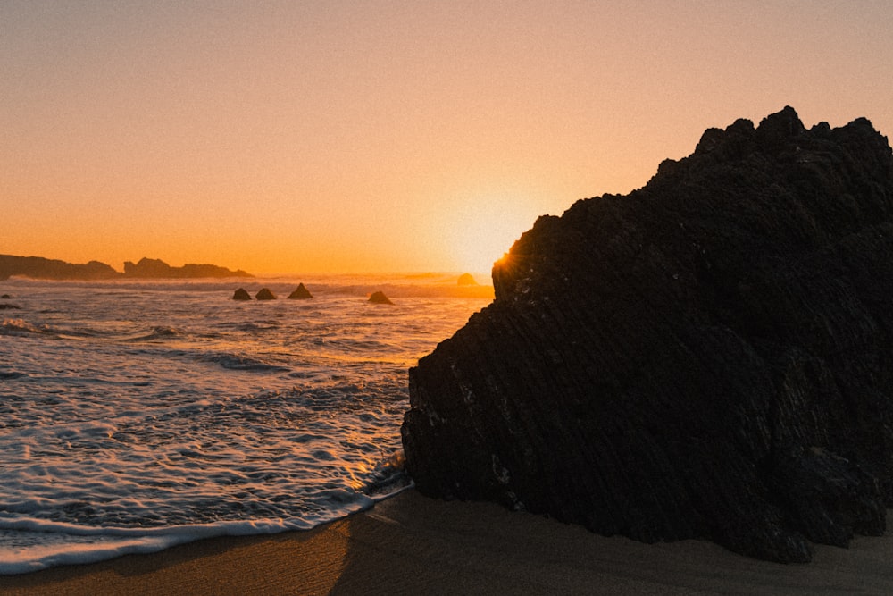 the sun is setting over the water at the beach