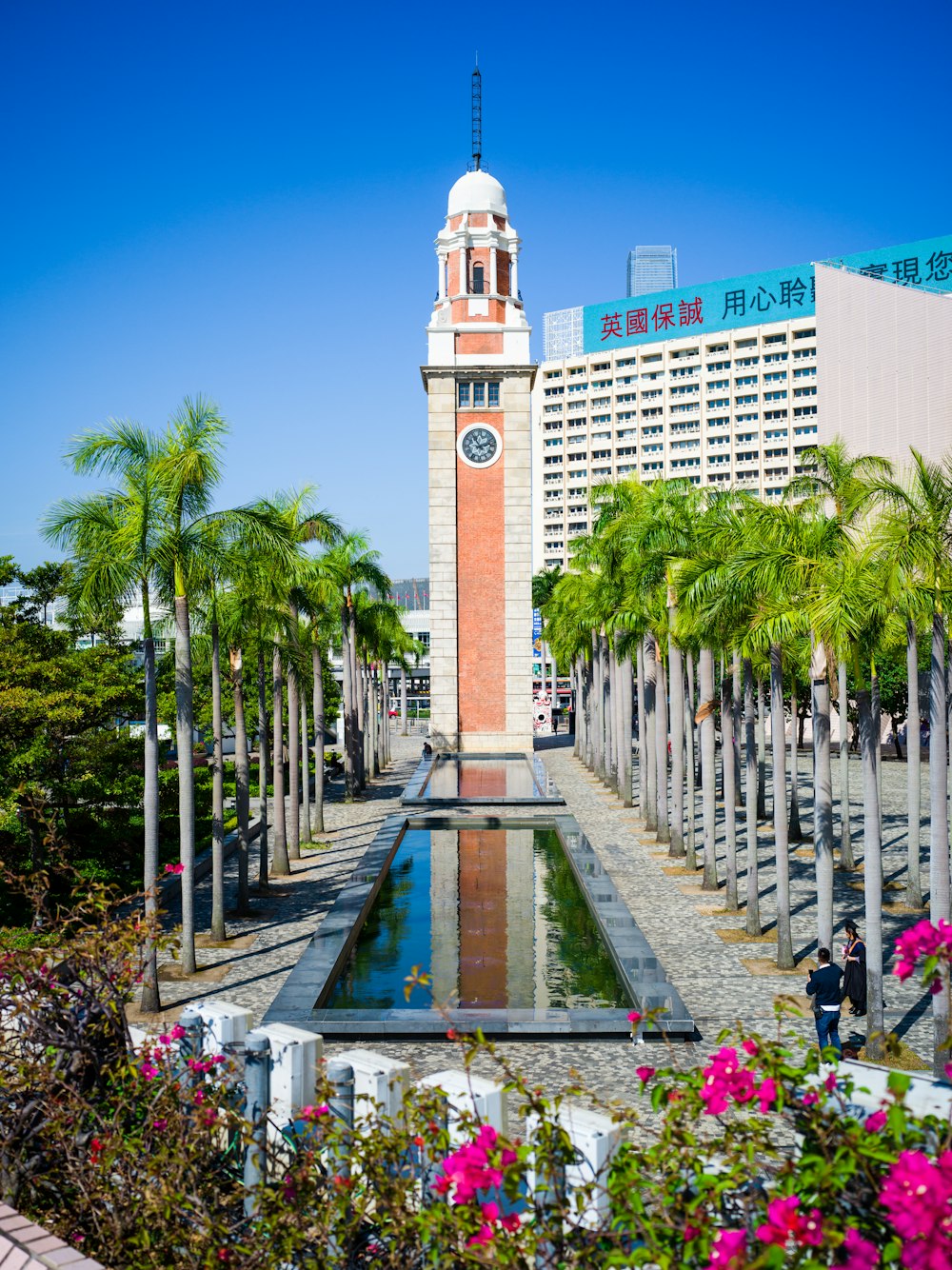 a tall clock tower sitting next to a pool of water