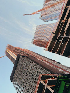 A panoramic view of a high-rise construction site in Riyadh with cranes and workers in action under a clear sky.