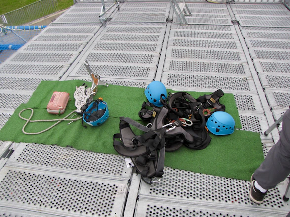 A vibrant display of climbing holds, harnesses, and helmets arranged on a wooden table.