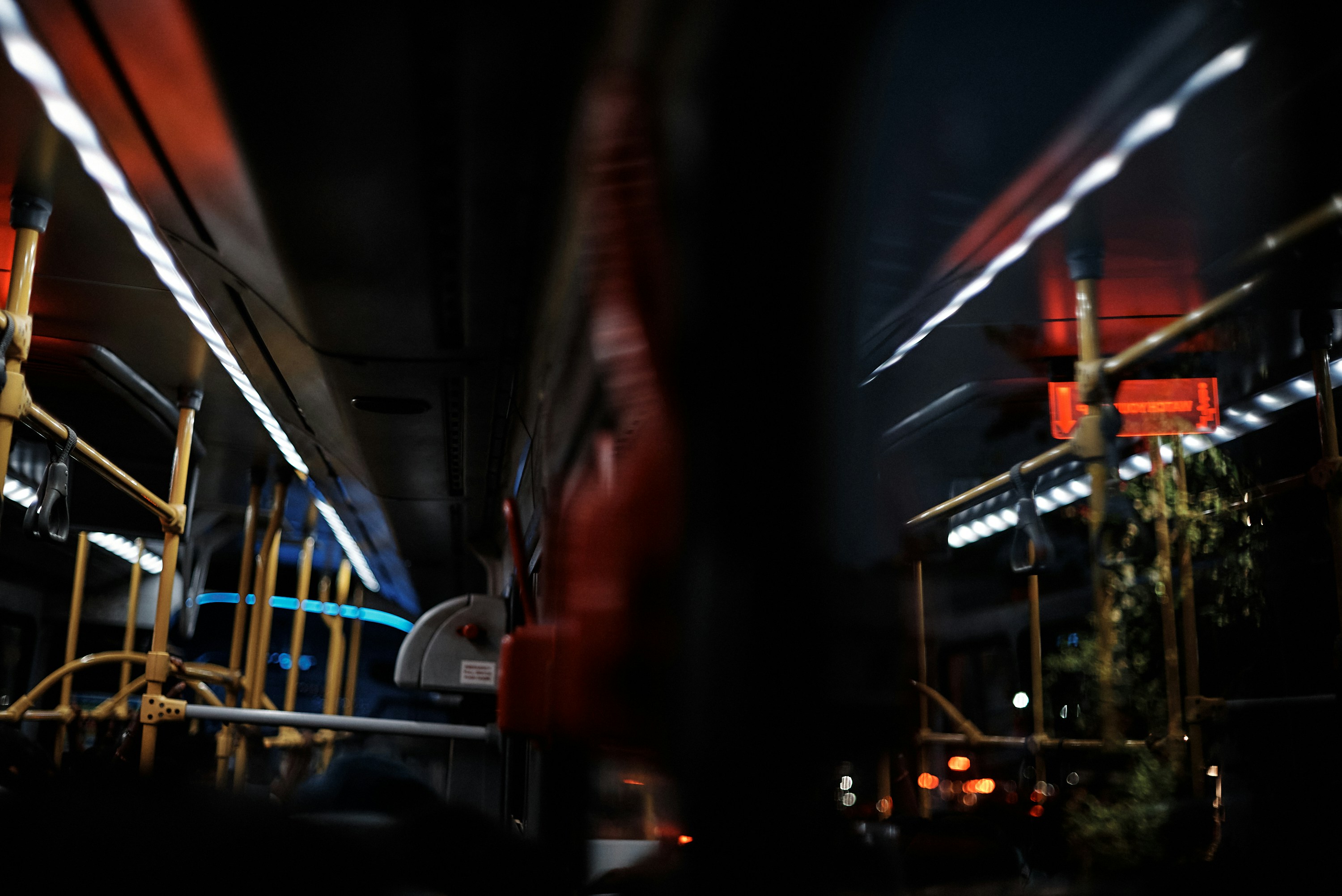 a blurry photo of a city bus at night, Lagos, Nigeria - 30.11.2021: Shots of the interiors, Close up of hand holding a handgrip, and a watch your step sign on a BRT, a mass transit system in Lagos, Nigeria.