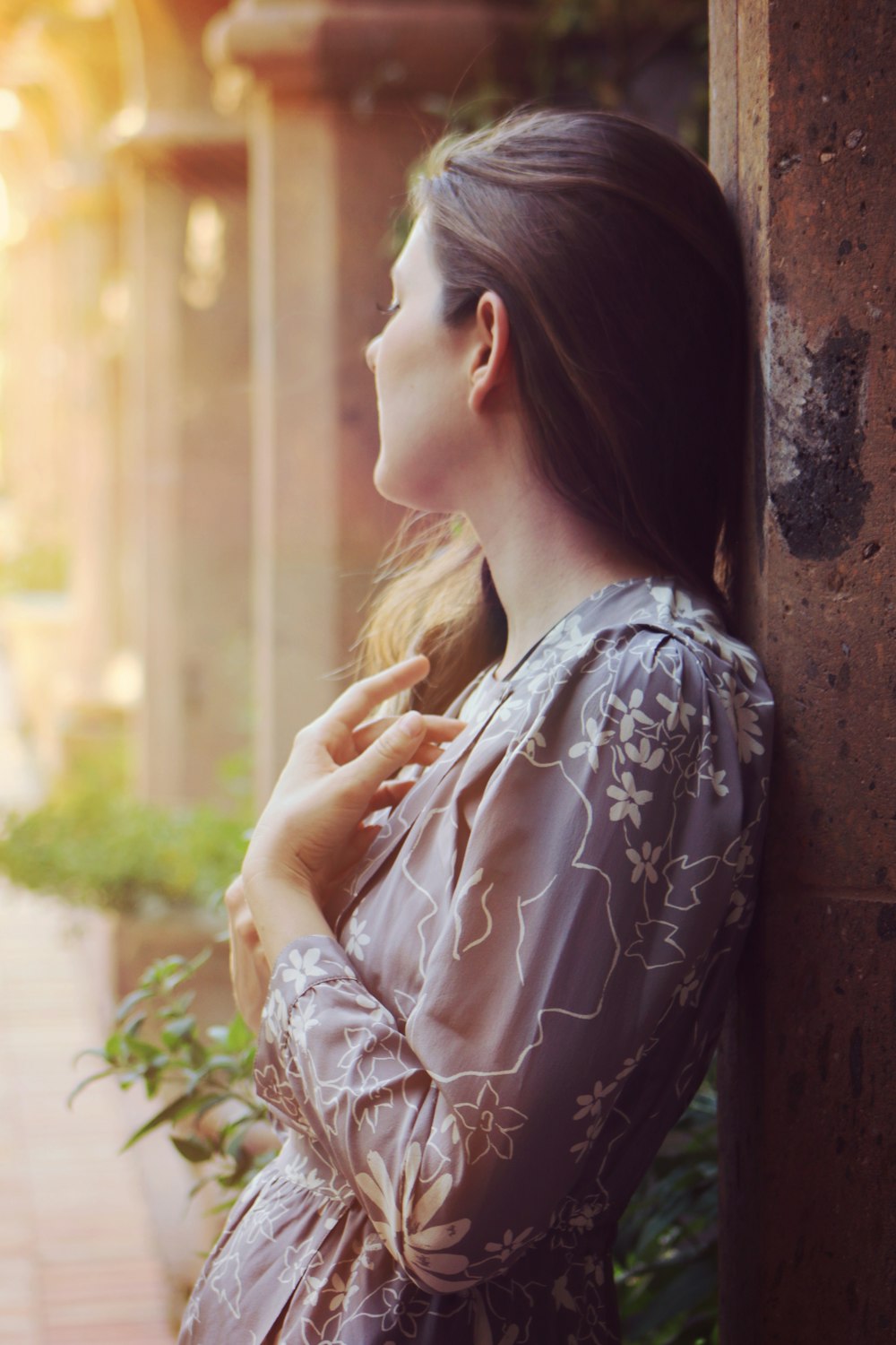 a woman leaning against a wall with her hand on her shoulder