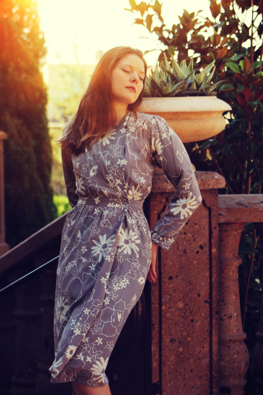 a woman in a dress leaning against a wall