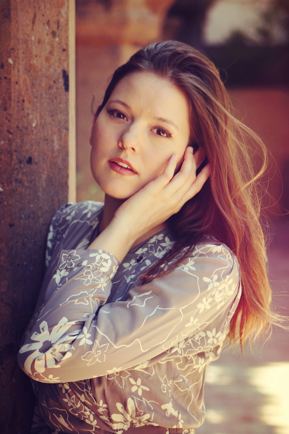 a woman leaning against a wall while talking on a cell phone