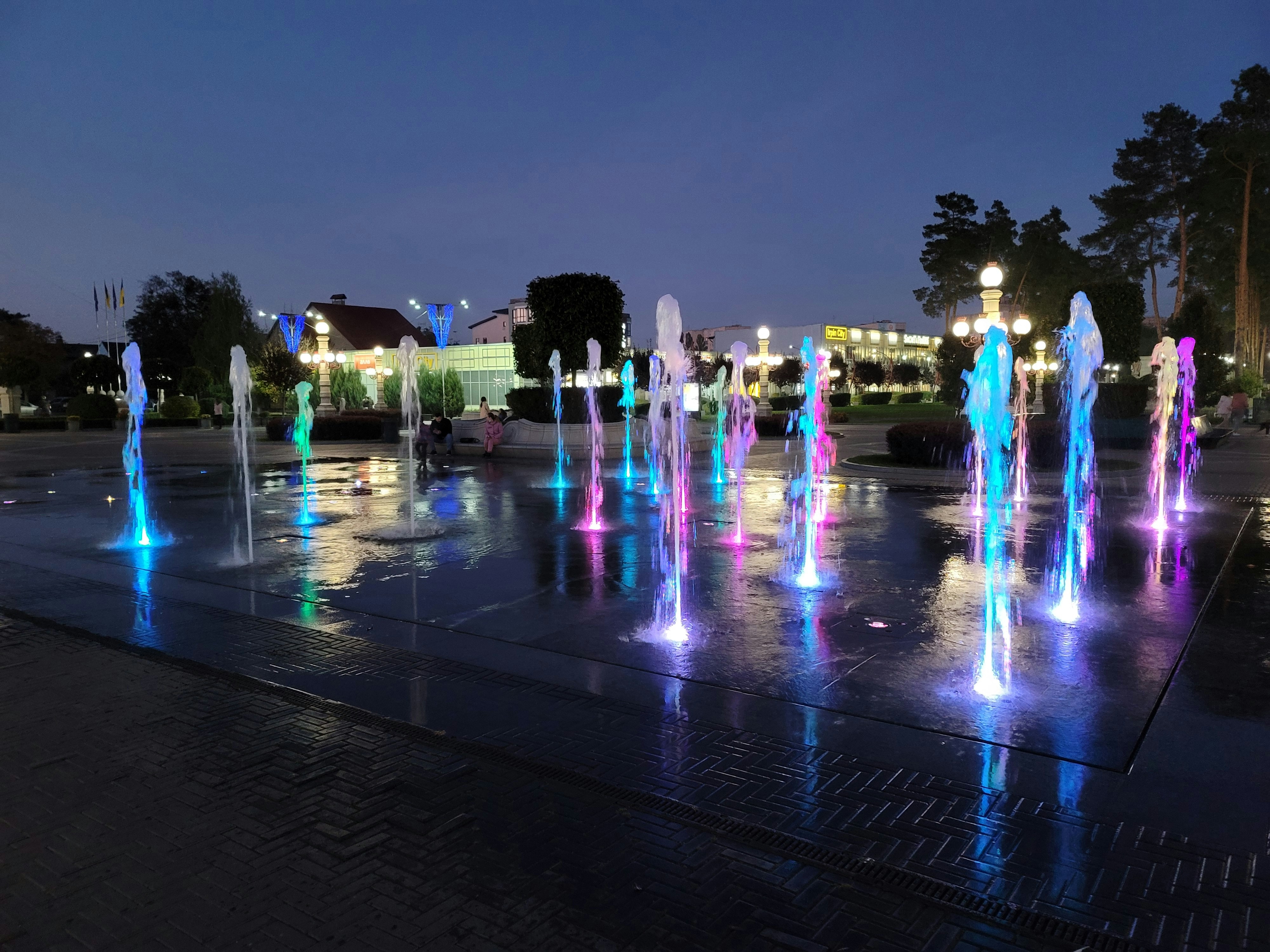 a group of water fountains in a park at night