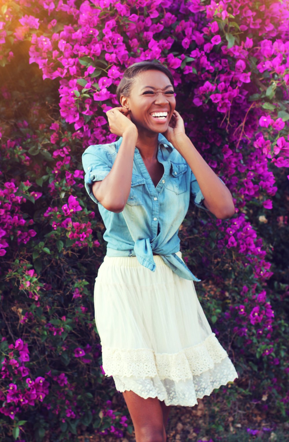 a woman standing in front of purple flowers talking on a cell phone