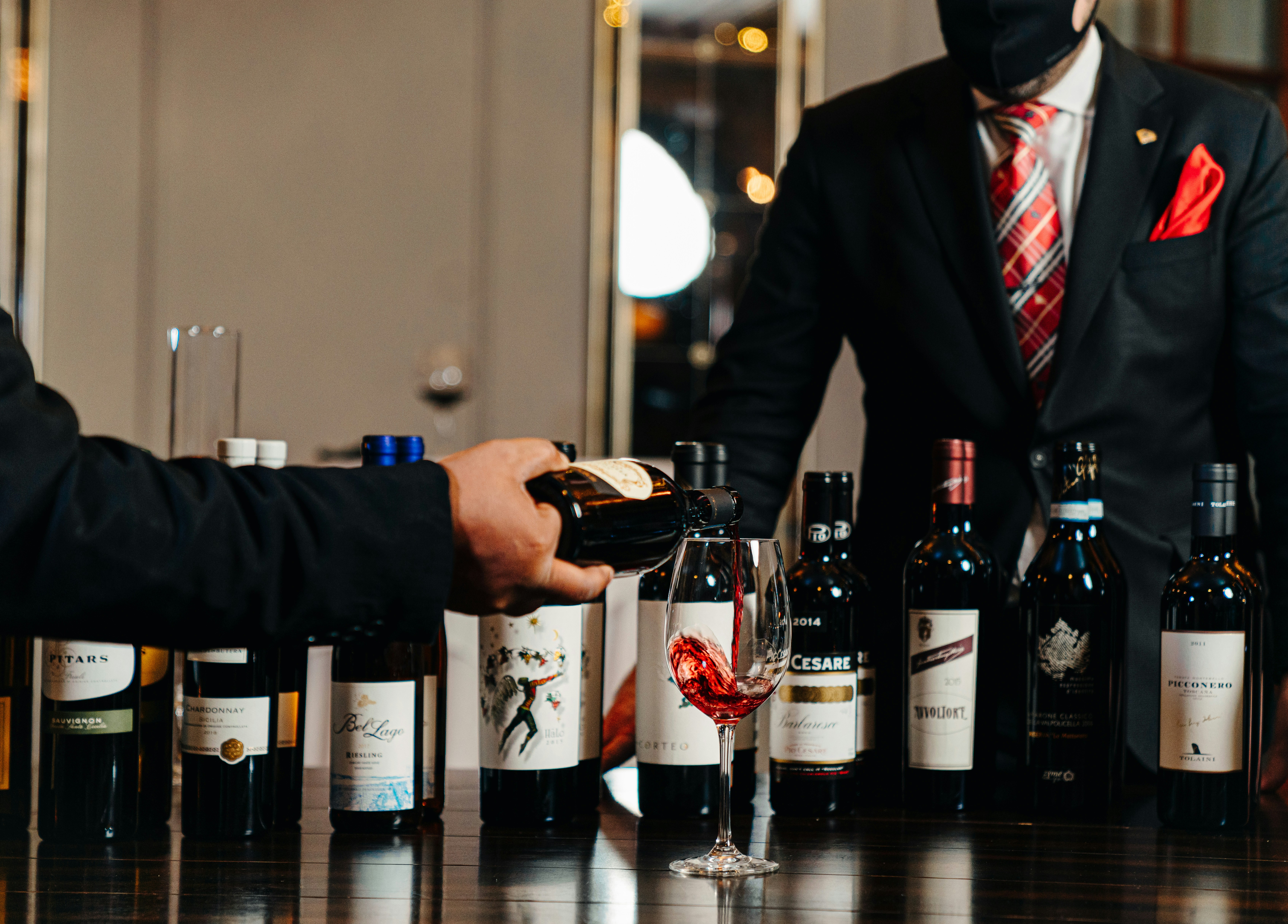 Un sommelier versa vino rosso in un bicchiere su un tavolo.