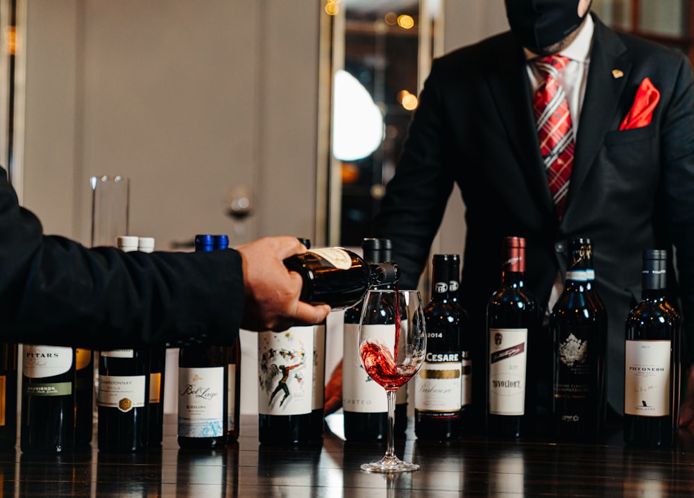 a man in a suit is pouring wine into a glass