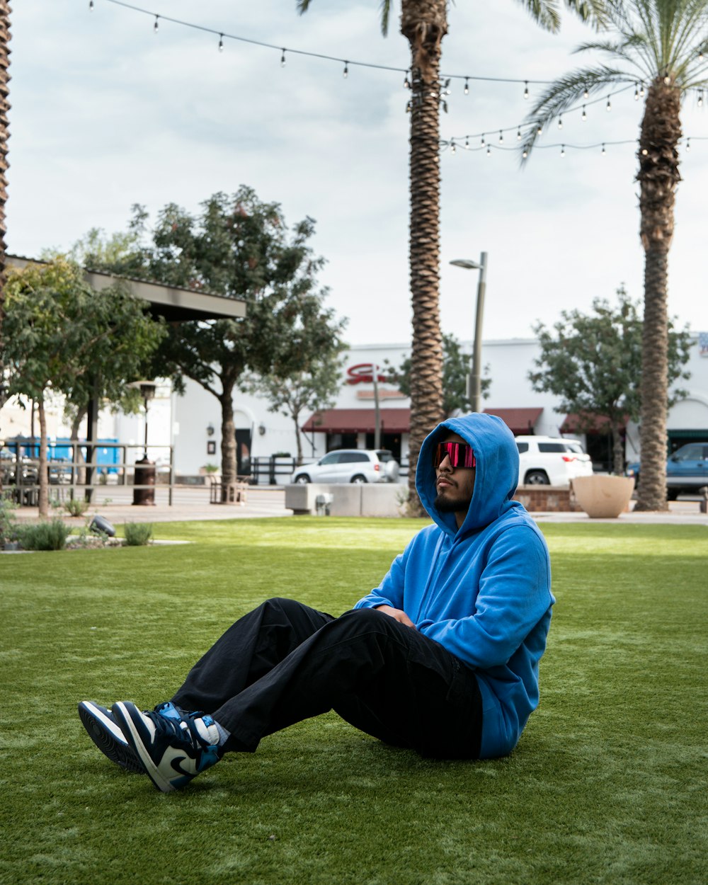 a man in a blue hoodie sitting on the grass