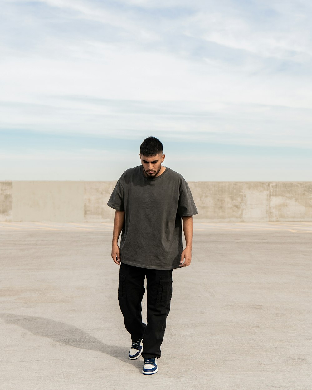 a man walking across a cement parking lot