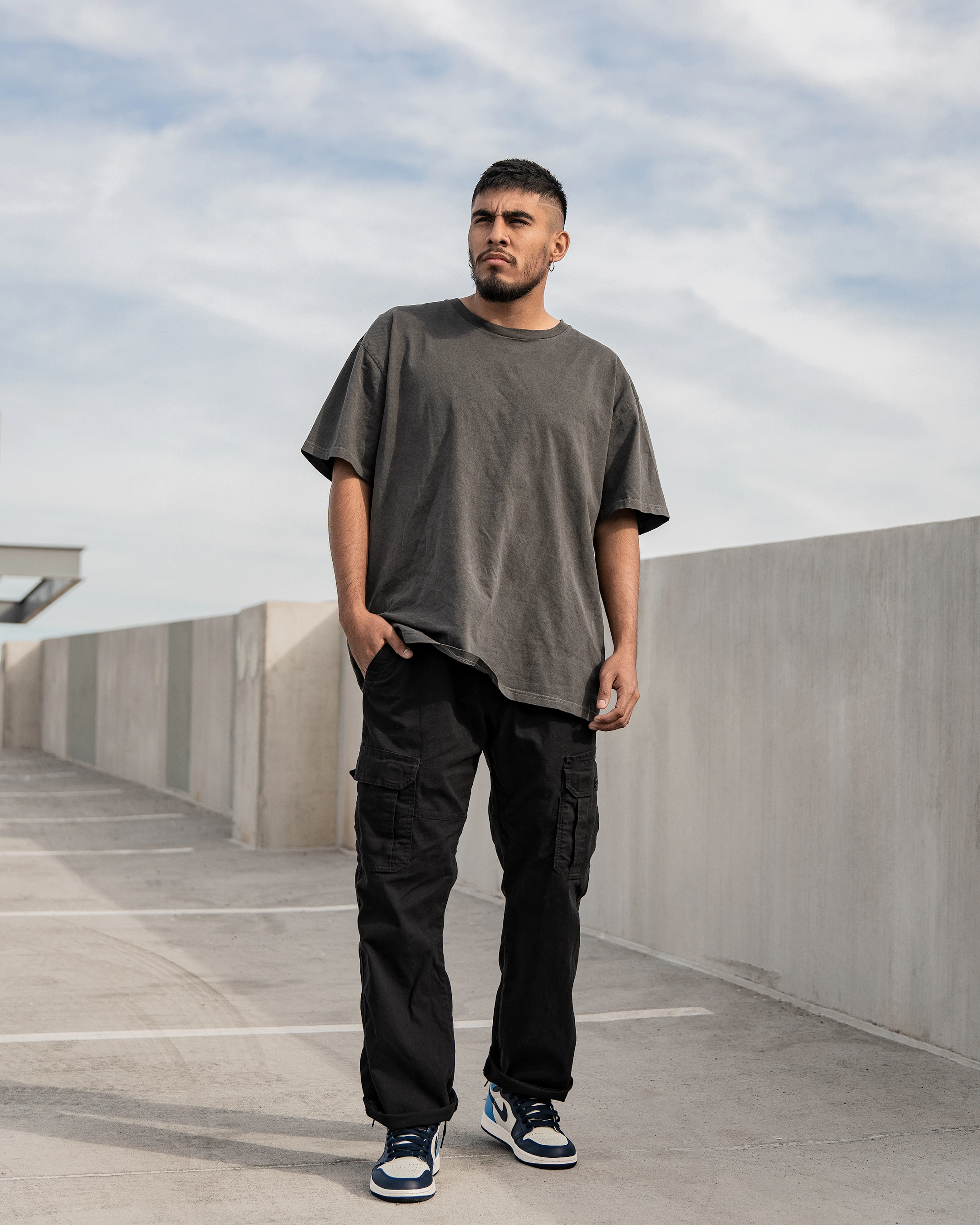 Man in an olive tee and black cargo pants on a rooftop