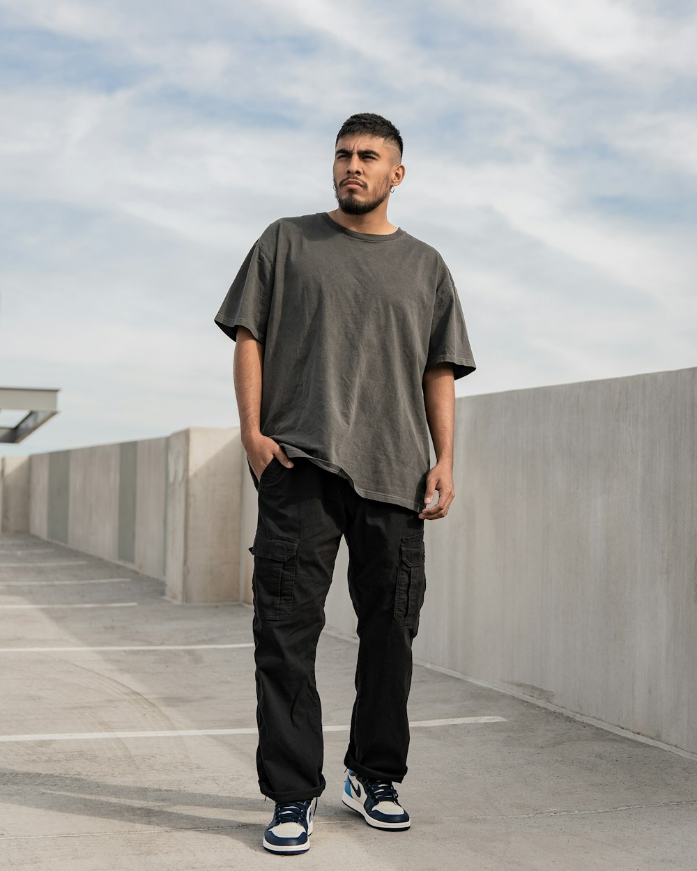 a man standing in a parking lot with his hands in his pockets