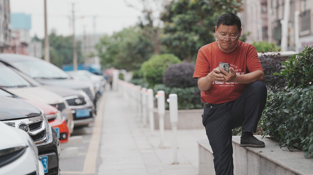 a man sitting on a wall looking at his cell phone