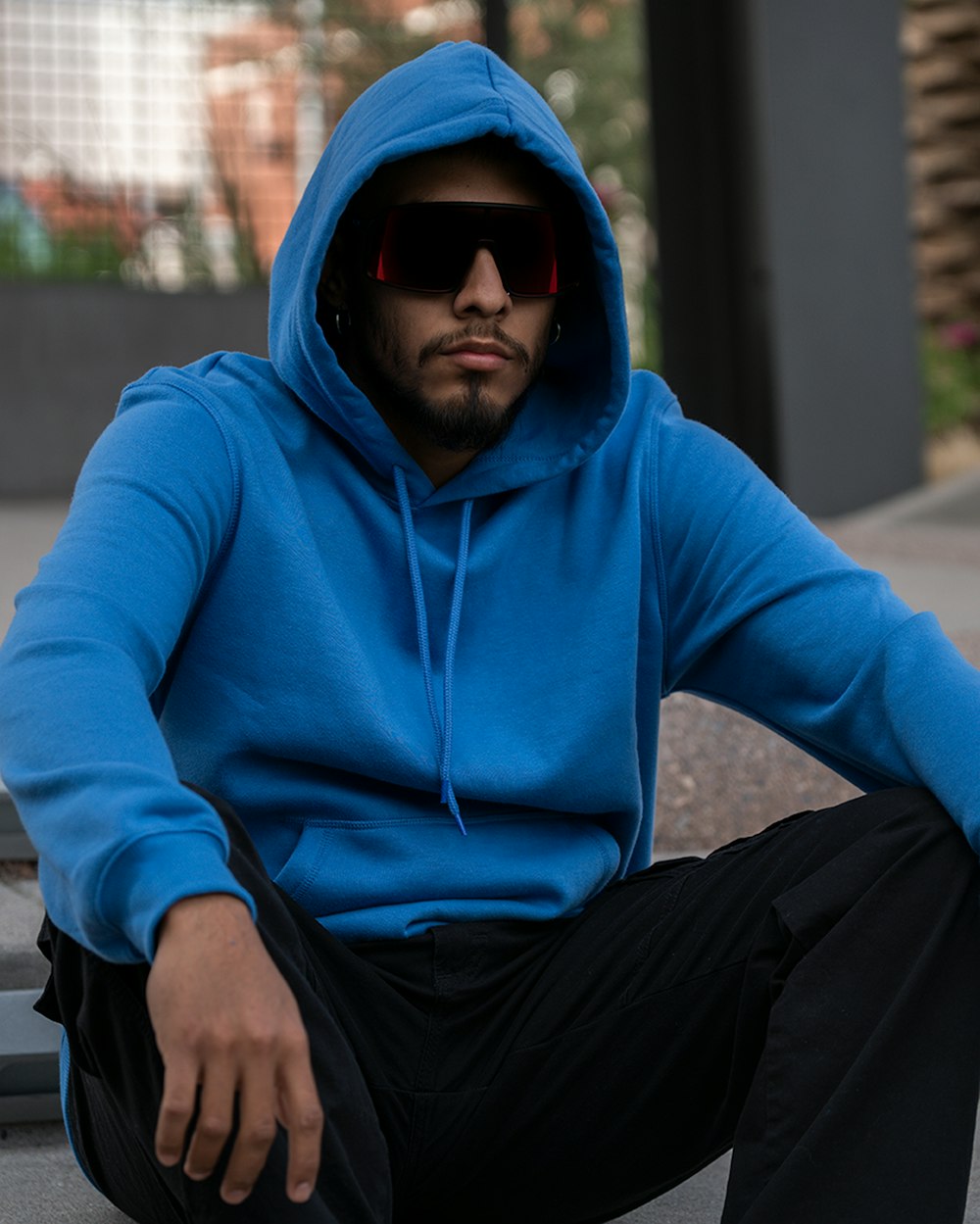 a man in a blue hoodie sitting on a bench