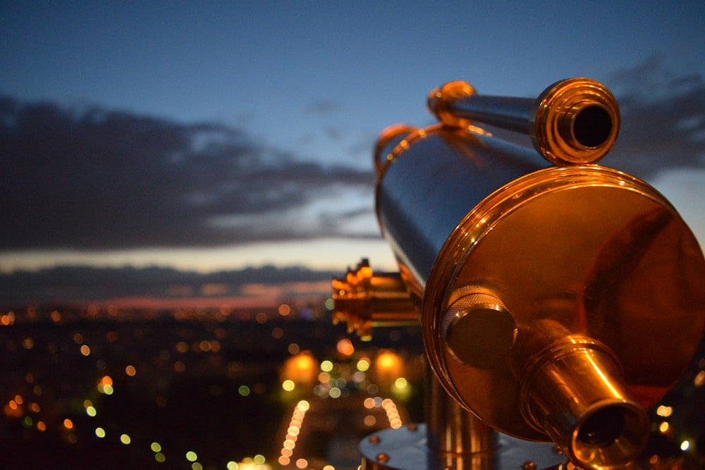 a close up of a telescope with a city in the background
