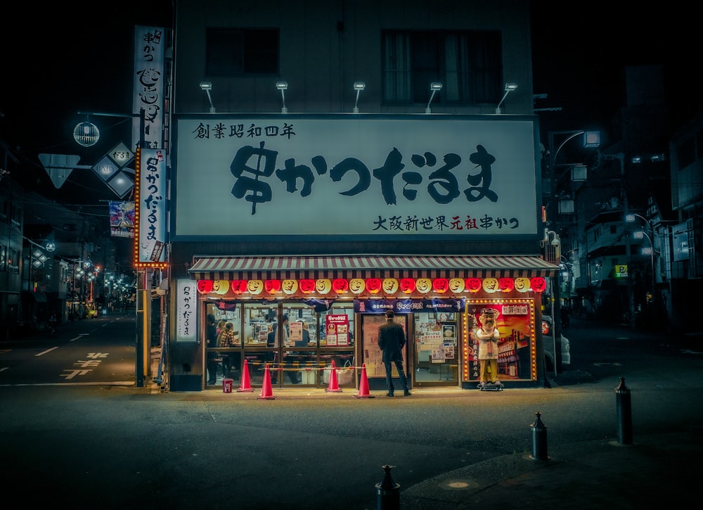 a man standing in front of a store at night