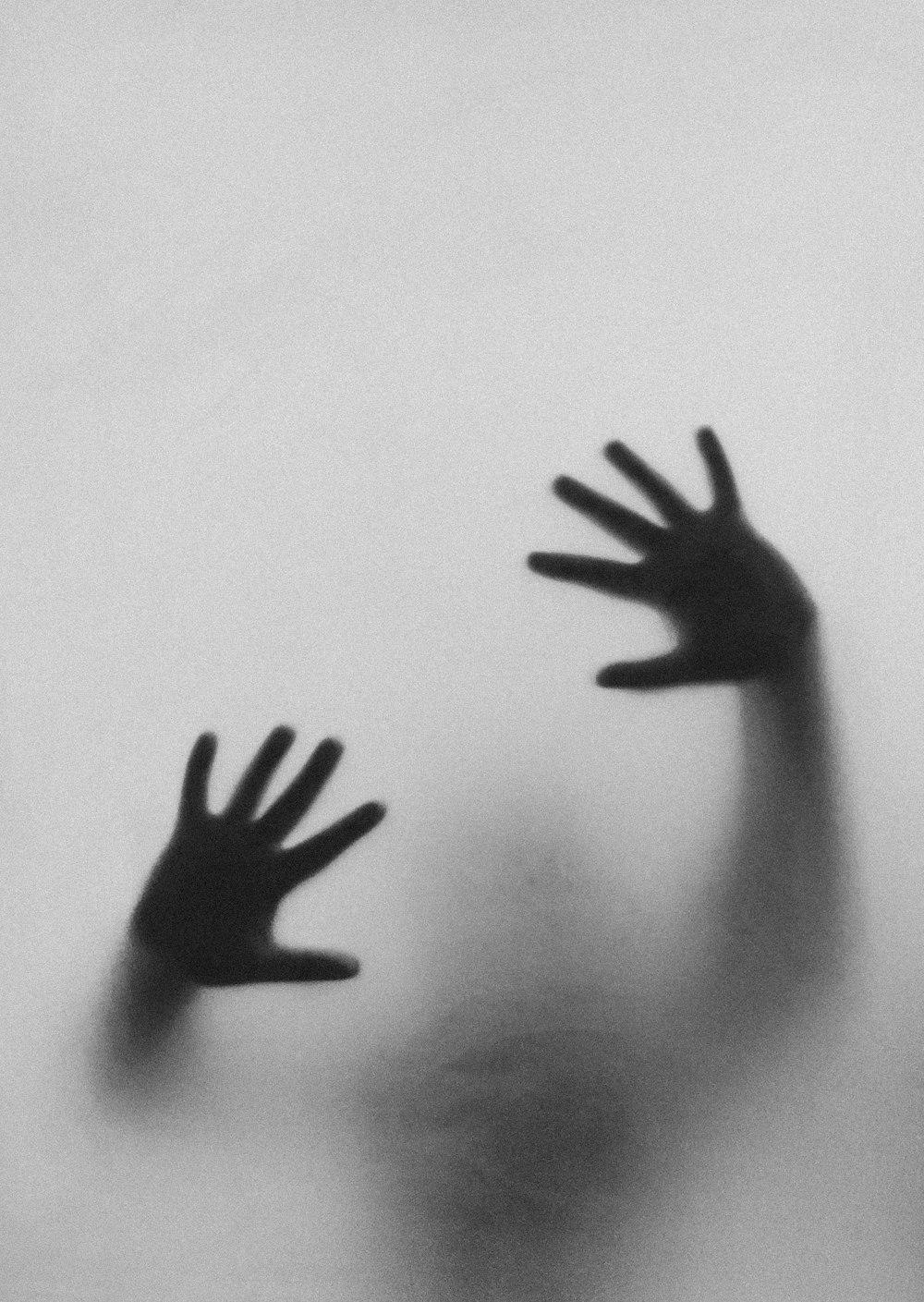 a black and white photo of two hands in the fog