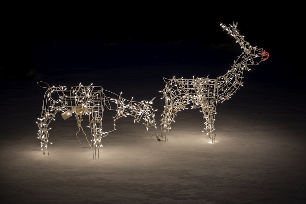 a couple of reindeer statues with lights on them