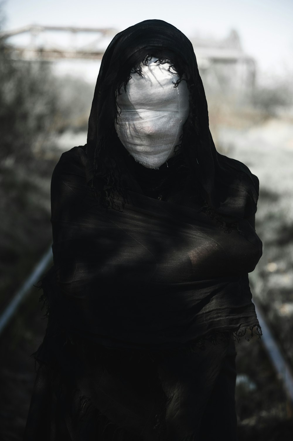 eine Person mit schwarzer Kapuzenjacke und weißer Maske