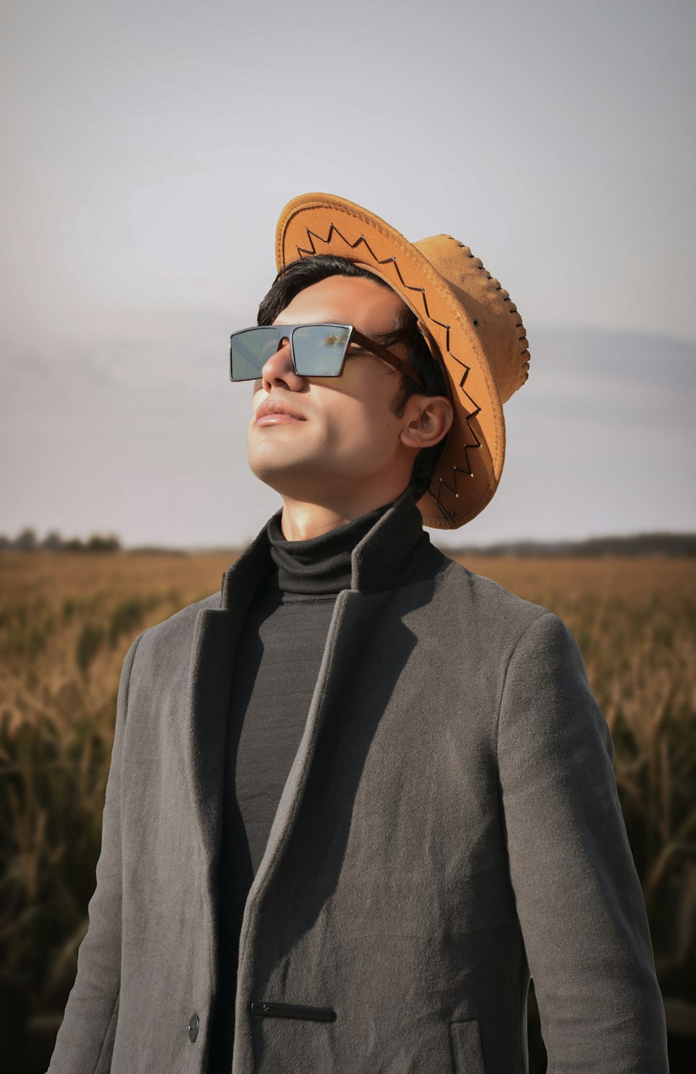 a man wearing a hat and sunglasses in a field