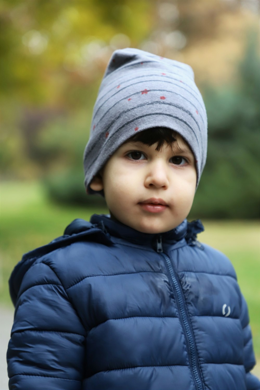 a young boy wearing a blue jacket and a gray hat