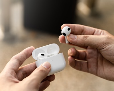 a person holding a pair of airpods in their hands