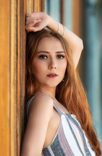 a beautiful young woman leaning against a wooden wall