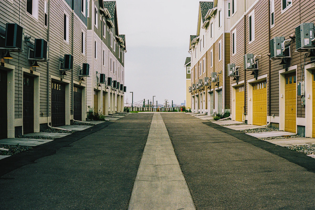 A quiet lane lined with multi-story townhome-style condominium buildings and garage doors