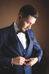 a man in a blue suit adjusts his tie
