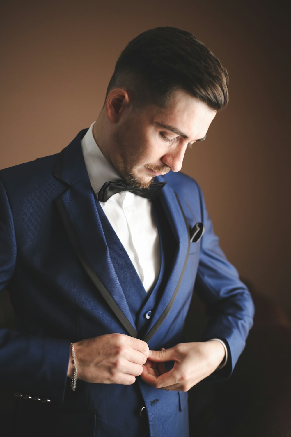 a man in a blue suit adjusts his tie