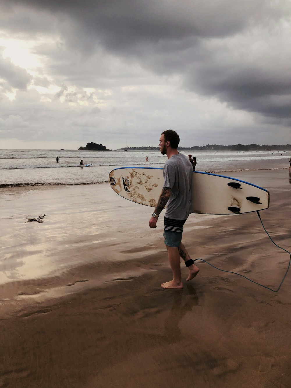 a man holding a surfboard on top of a sandy beach