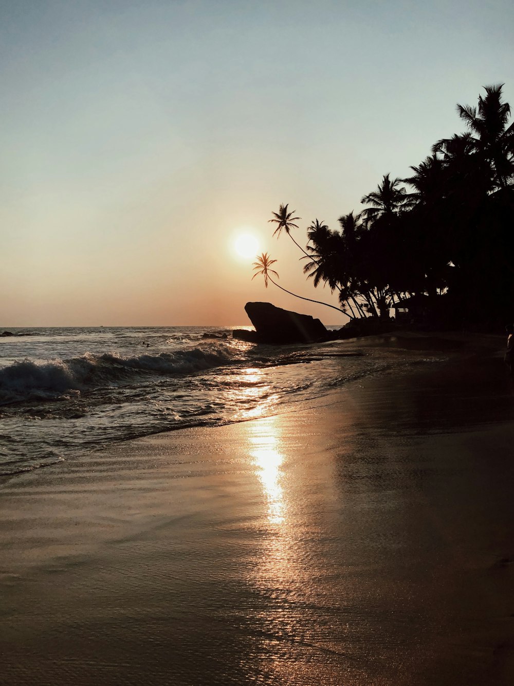 the sun is setting on a tropical beach