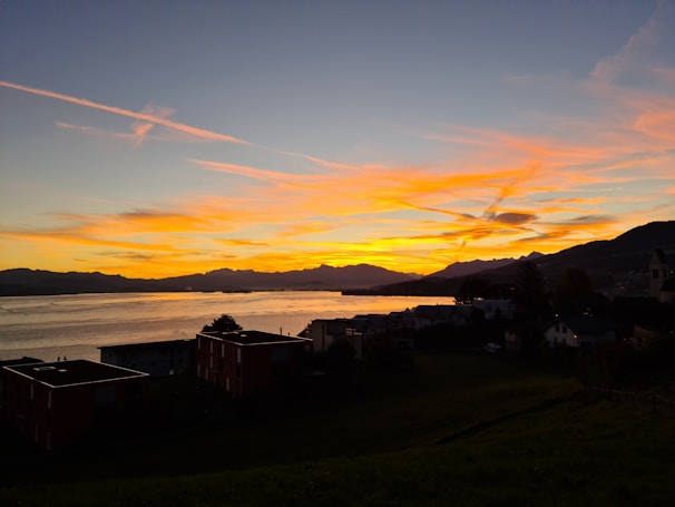 A serene landscape of Barcelona’s coastline at sunset, with vibrant colors reflecting on the water.