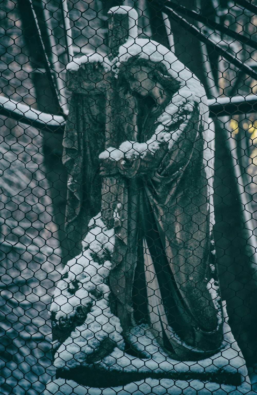 a statue of a man standing behind a chain link fence