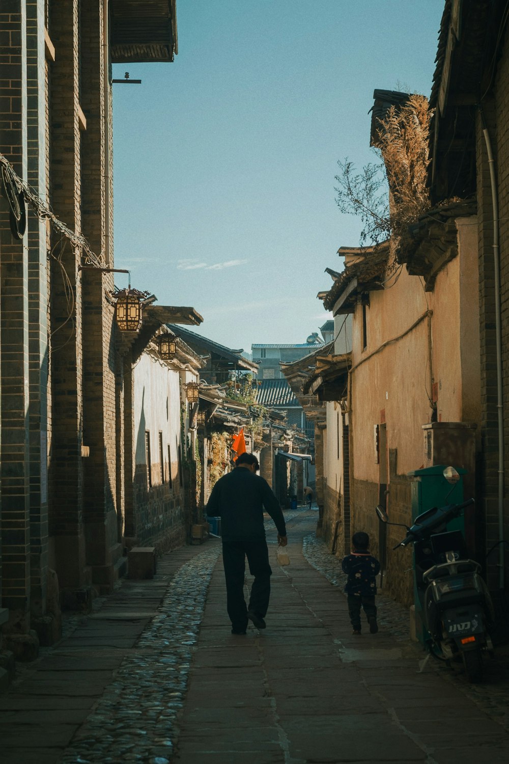 a man walking down a street next to tall buildings