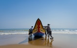 a group of people standing next to a boat on a beach