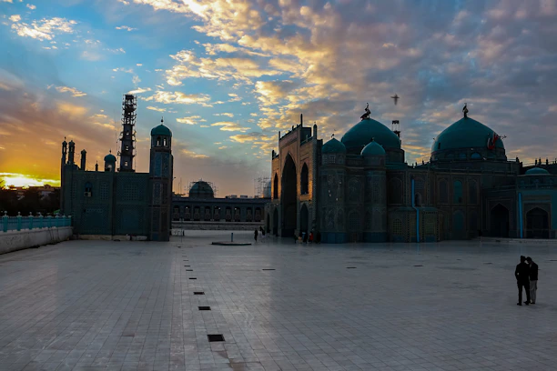 A serene mosque courtyard bathed in soft golden light during sunset.