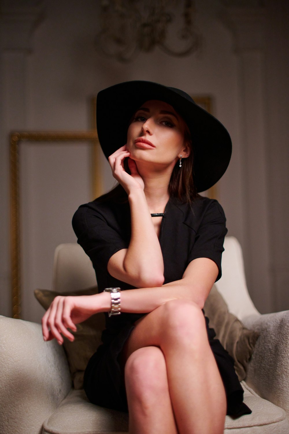 a woman sitting on a couch wearing a black hat