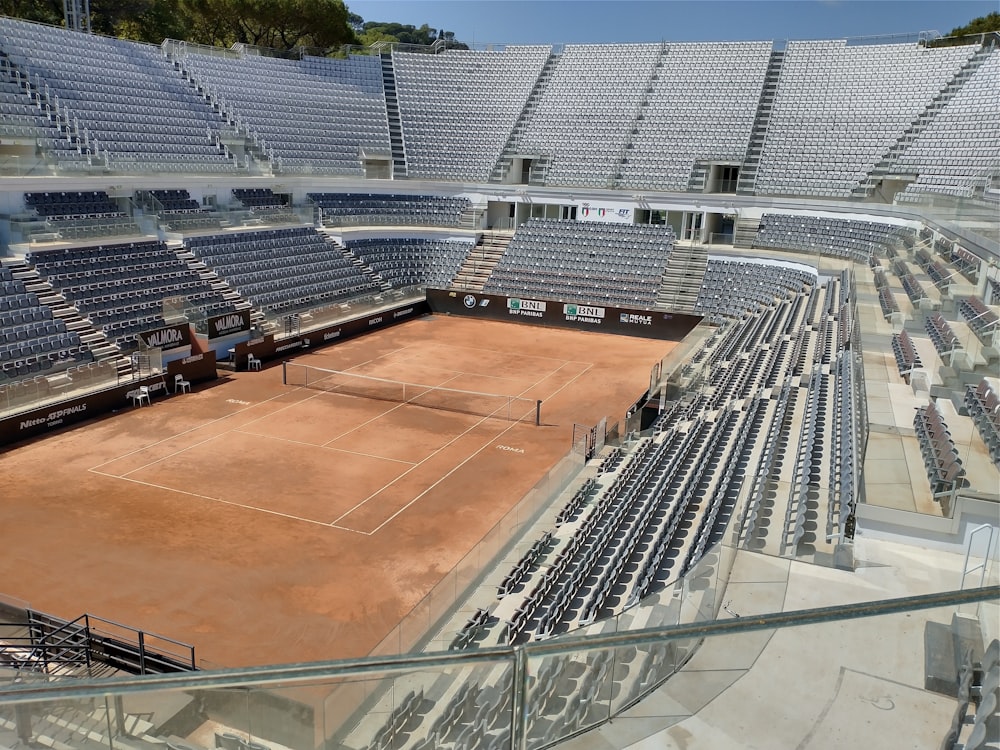 an empty tennis court surrounded by rows of empty seats
