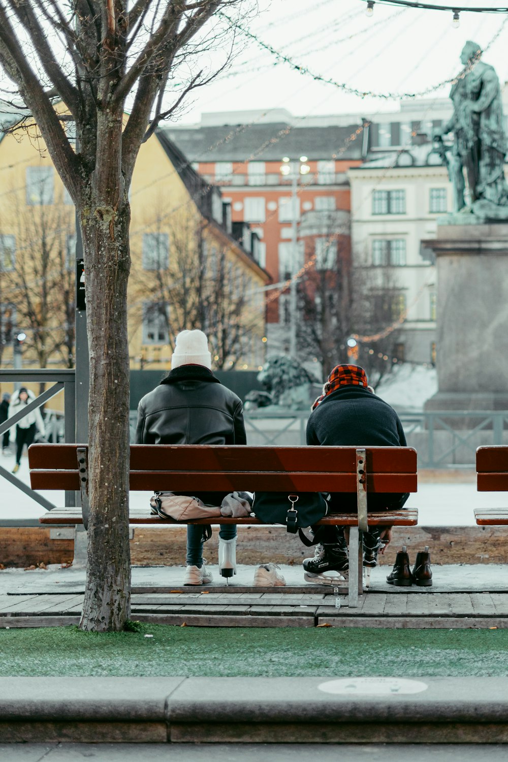 two people sitting on a bench near a tree