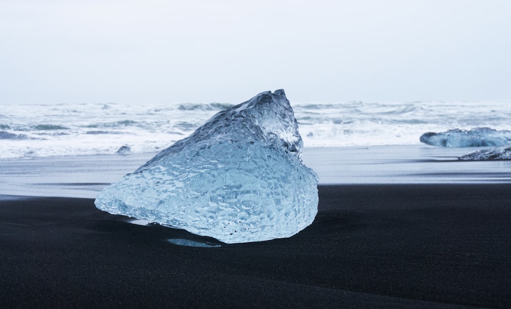a large iceberg sitting on top of a black sand beach