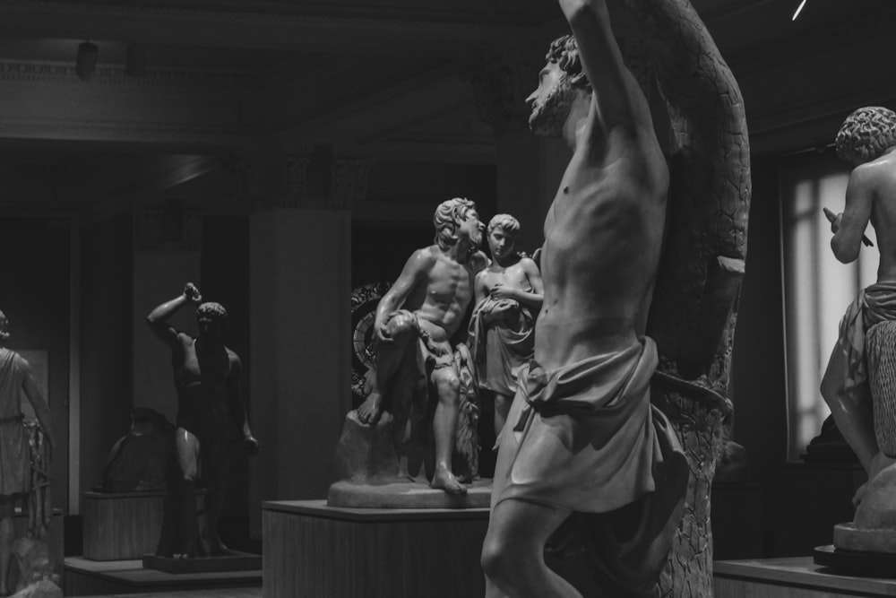 a black and white photo of statues in a museum