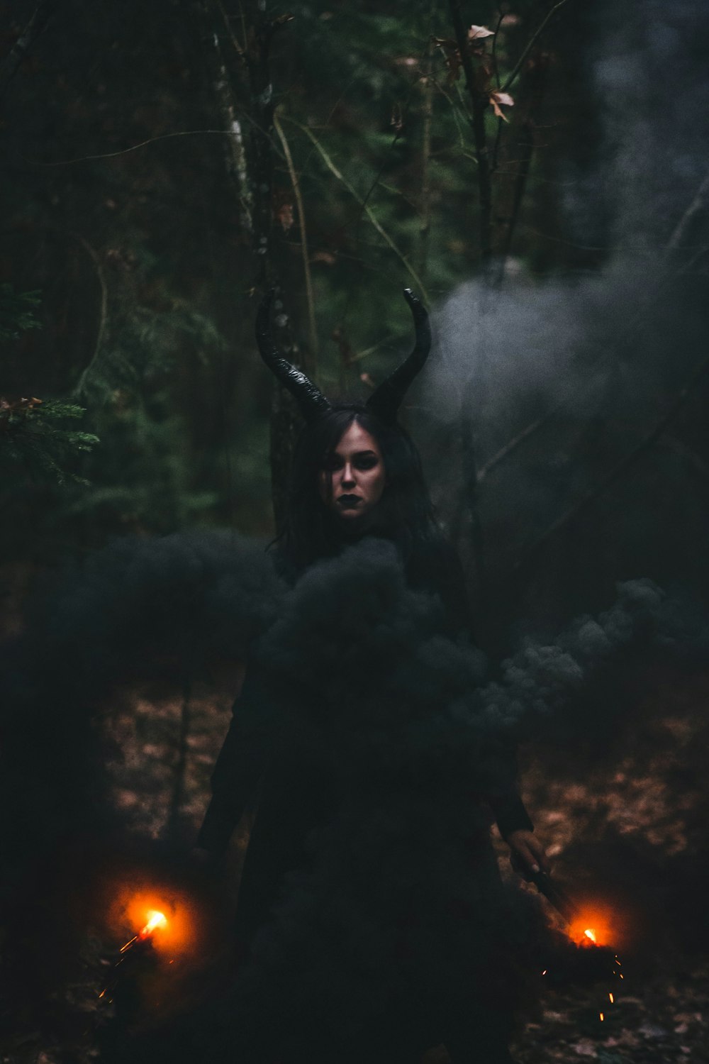 a woman with horns standing in the woods