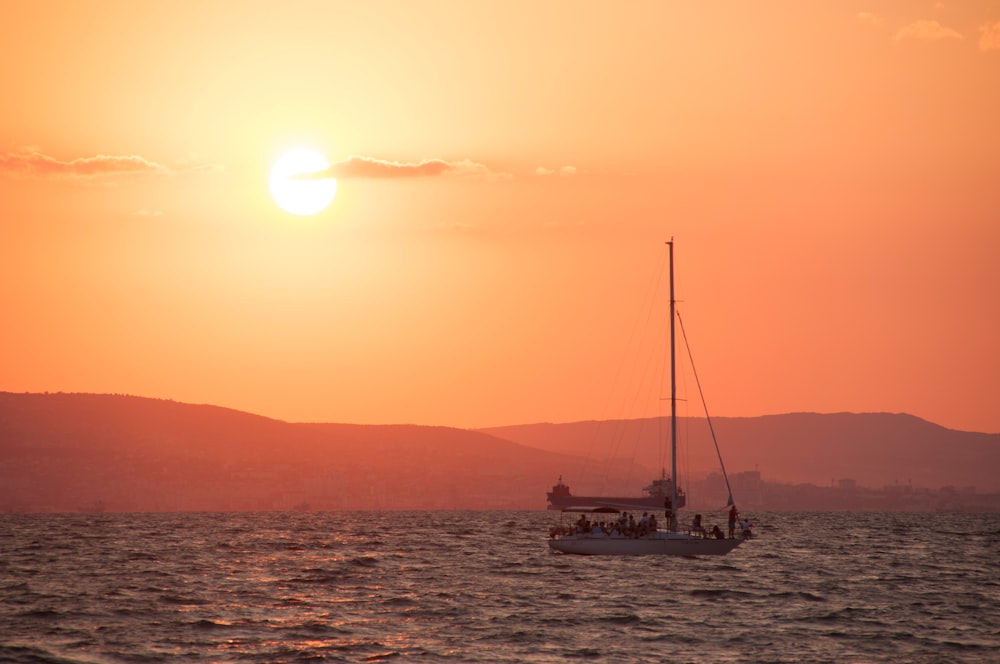 a sailboat in the ocean at sunset