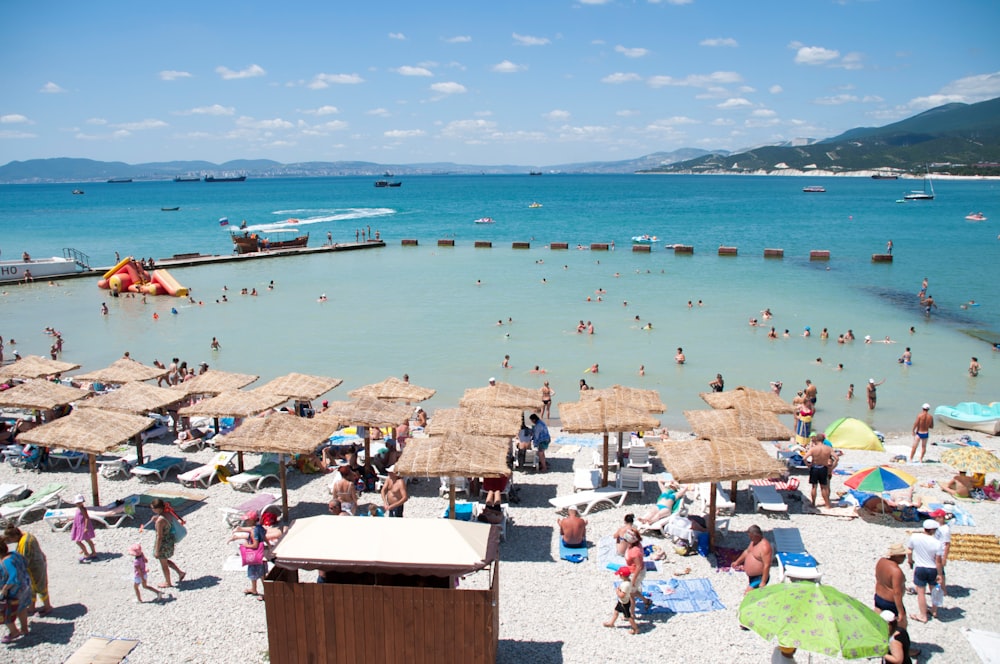 a crowded beach with umbrellas and people in the water