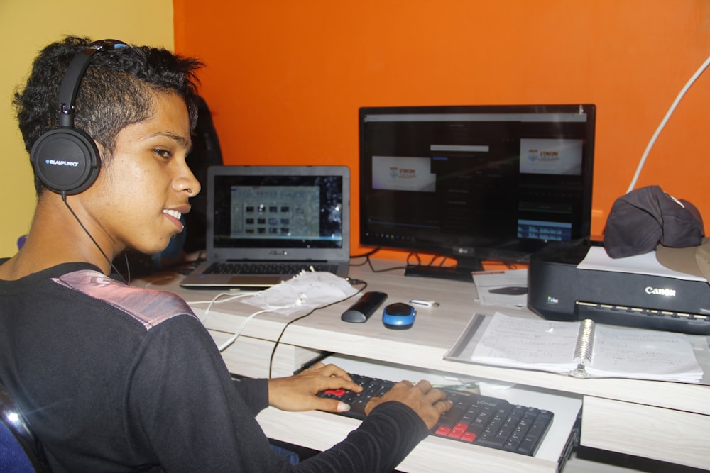 a young man sitting at a desk with headphones on